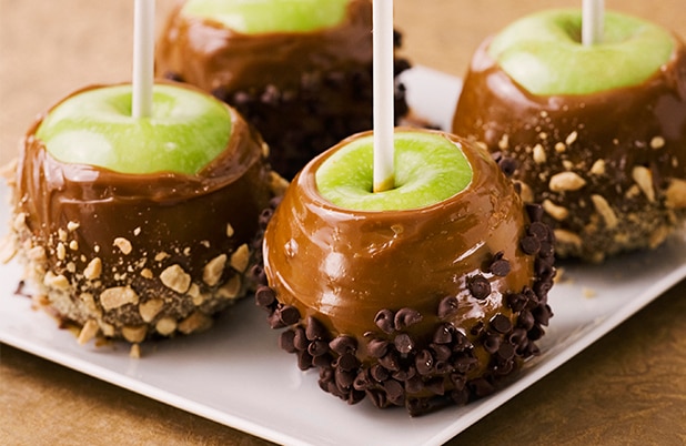 Green apples on a stick dipped in caramel, nuts and chocolate chips.